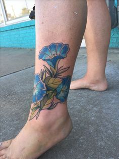 a woman's foot with a blue flower tattoo on her left leg and right leg