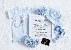 a baby announcement with blue shoes, booties and t - shirt on snow covered ground