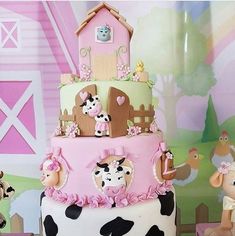 a three tiered cake decorated with farm animals and pink icing on a table