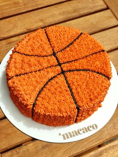 a basketball cake on a white plate sitting on a wooden table