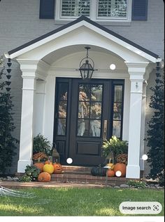 a front door with pumpkins and gourds on the steps