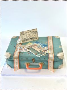 a cake shaped like an old suitcase with pictures on top and writing on the lid