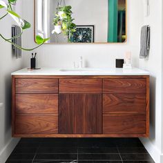 a bathroom with a sink, mirror and plants in the corner on the counter top