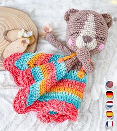 a crocheted teddy bear laying on top of a blanket next to other items