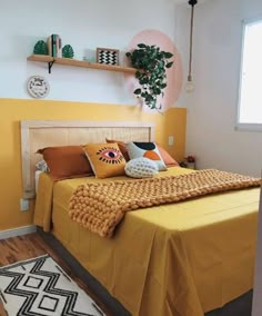 a bed with yellow sheets and pillows on top of it in a room that has wooden floors