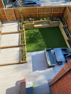 an overhead view of a small backyard with grass and wooden fenced in area for seating