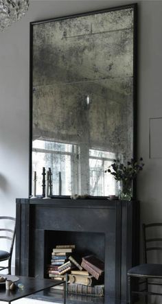 a living room filled with furniture and a large mirror over the fire place in front of a fireplace