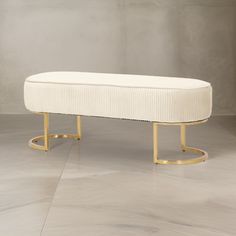 a white bench sitting on top of a hard wood floor next to a gray wall