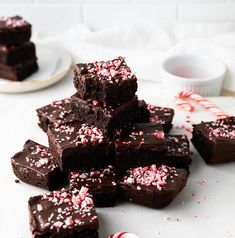 a pile of brownies with sprinkles and candy cane on the side