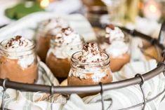 four desserts in small glass jars sitting on a table