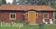 a small red house with a yellow door and brown shingles on the roof is surrounded by greenery