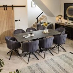 a dining room table with chairs and a rug on the floor