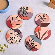 four coasters with different designs on them next to a cup of coffee and flowers