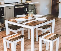 a kitchen table with four chairs and two plates on top of it, in front of an oven