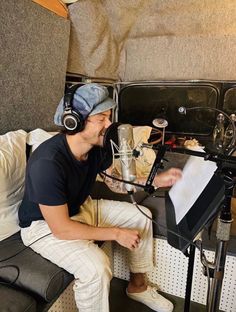 a man with headphones on sitting in front of a microphone and recording equipment,