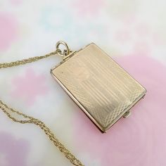 Four photos can be held within this antique gold filled locket pendant fob. The large rectangle pendant measures 1 9/16 (not including bail) inches by 1 1/8 inches and hangs from a 14k gold filled chain. The inside has a hinged frame with oval opening, in which two photos could be placed back to back. The rectangle panels can also hold large images. The front is linear engraved with a blank circular area meant for a monogram. There is a slight dimple and surface scratches to the front. The back is plain, also with a ding and visible scratches. The locket closes, but slightly askew, leaving a gap. The pendant hangs from a hinged triangle bail and large jump ring. The vintage twisted rope chain stretches 17 1/2 inches long and closes with a spring ring/end hallmarked, "1/20 14k GF, 14/20 GF" Gold Rectangular Locket Necklace, Locket Gold, Hinged Frame, Rectangle Pendant, Photo Locket, Locket Necklace, Rope Chain, Spring Rings, Antique Gold