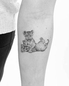 a woman's leg with a small tattoo of two kittens and a mouse on it