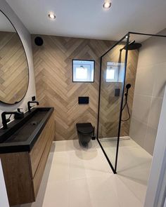 a bathroom with a toilet, sink and shower in it's own area that has wood paneling on the walls