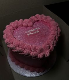 a pink heart shaped cake sitting on top of a table