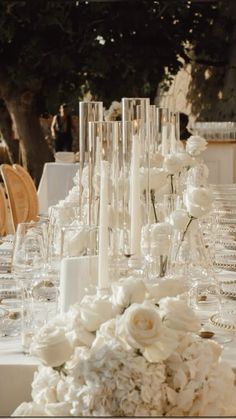 the table is set with white flowers and wine glasses for an elegant wedding reception or special event