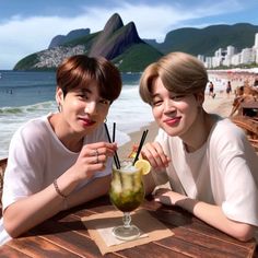 two young men sitting at a table with drinks in front of them on the beach