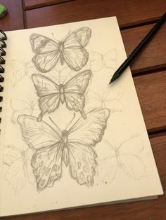 a pencil drawing of three butterflies sitting on top of a notebook