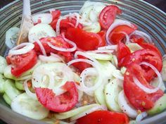 a bowl filled with cucumbers, tomatoes and onions