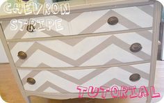 a chevron stripe dresser painted white and gray with pink lettering on the bottom drawer