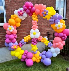 the letter o made out of balloons in front of a brick building with a black gate