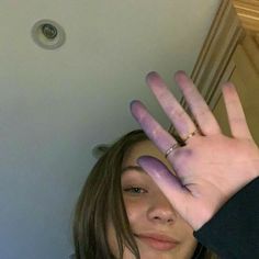 a woman holding her hand up in the air with purple paint on it's hands