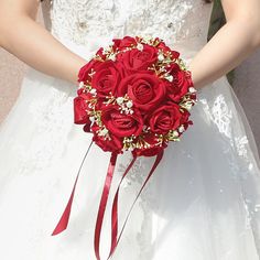 a bride holding a bouquet of red roses