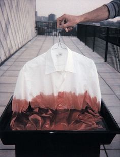 a person holding a shirt on a grill with red and white dye over the top