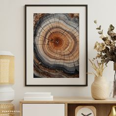 a wooden table topped with a vase filled with flowers next to a framed art piece