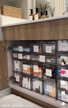 an organized cabinet with clear drawers and labels on the bottom, filled with personal care items