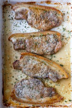 three pieces of meat sitting on top of a baking pan covered in gravy