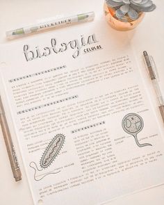 a close up of a paper with writing on it next to a pen and a plant