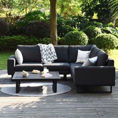 a black couch sitting on top of a wooden floor next to a table and chairs