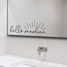 a bathroom with a white sink and large mirror above the sink is a hello sunshine wall decal