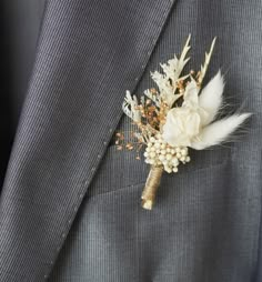 a boutonniere with white flowers and feathers on the lapel of a suit