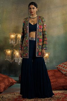 "Featuring a multi-colored jacket in silk base with mirror, sequins and cutdana embellishments. It is paired with a prussian blue georgette crop top and sharara pants. Accentuate this designer jacket set with dangler earrings and block heels for a festive look.#Perniaspopupshop #womenswear #ethnic #whatiworewastrending #ppuslove #jacketset #Georgette #designerjacket #weddingwear #festivewear Chaniya Choli With Blazer, Jacket And Crop Top Outfit, Velvet Jackets Women Indian, Sharara With Jacket, Sleeveless Jacket Outfit, Georgette Crop Top, Jacket Sharara, Velvet Jackets Women, Mirror Work Dress