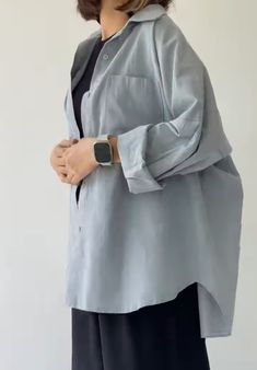 a woman wearing a gray jacket and black pants standing with her hands on her hips