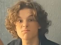 a woman with curly hair is looking at the camera