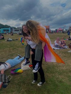 two women hug each other in the middle of a field with people laying on the ground