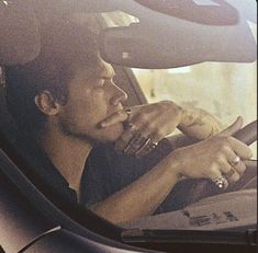 a man sitting in the driver's seat of a car talking on his cell phone