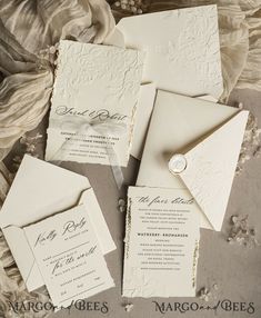 the wedding stationery is laid out on top of an old piece of cloth and paper