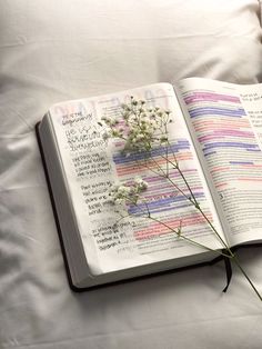 an open book with writing on it sitting on a bed next to a flower bouquet