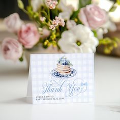 a thank you card sitting on top of a table next to a bouquet of flowers