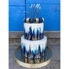 a three tiered blue and white cake with gold decorations on it's sides