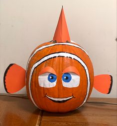 a pumpkin with an orange hat on it's head sitting on a wooden table