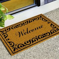 a welcome mat sitting next to a potted plant